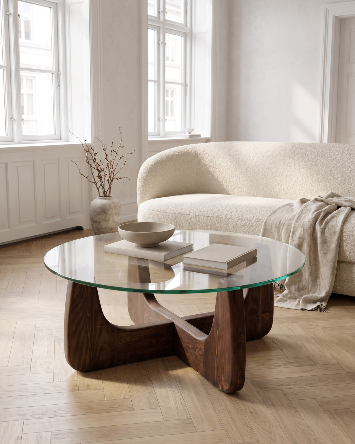 Selene round coffee table with clear glass top and sculptural walnut-finish cross base in a bright living room