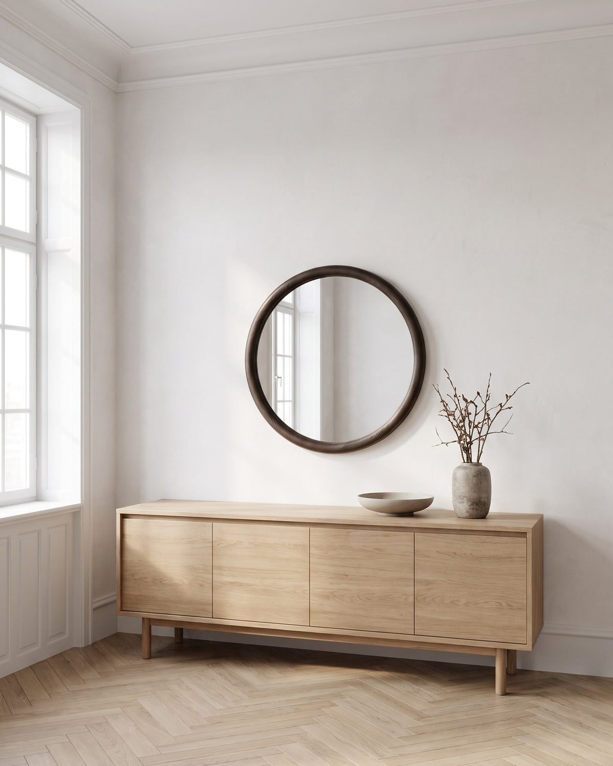 Enso round wall mirror with dark wood frame above a light oak sideboard in a bright living room