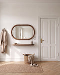 Specchio ovale Livia 110 × 70 cm con mensola sospesa color noce in un ingresso, chiavi in una ciotola, cappotto appeso e panca in rovere