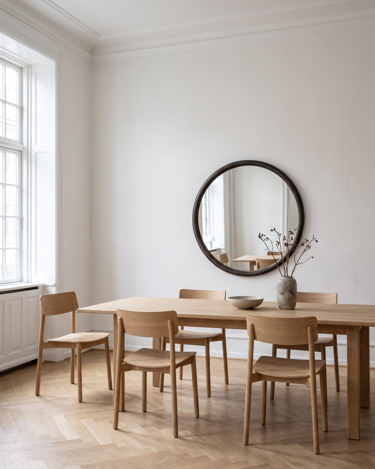 Enso round wooden mirror Ø 70 cm on the wall of a bright dining room above an oak dining table