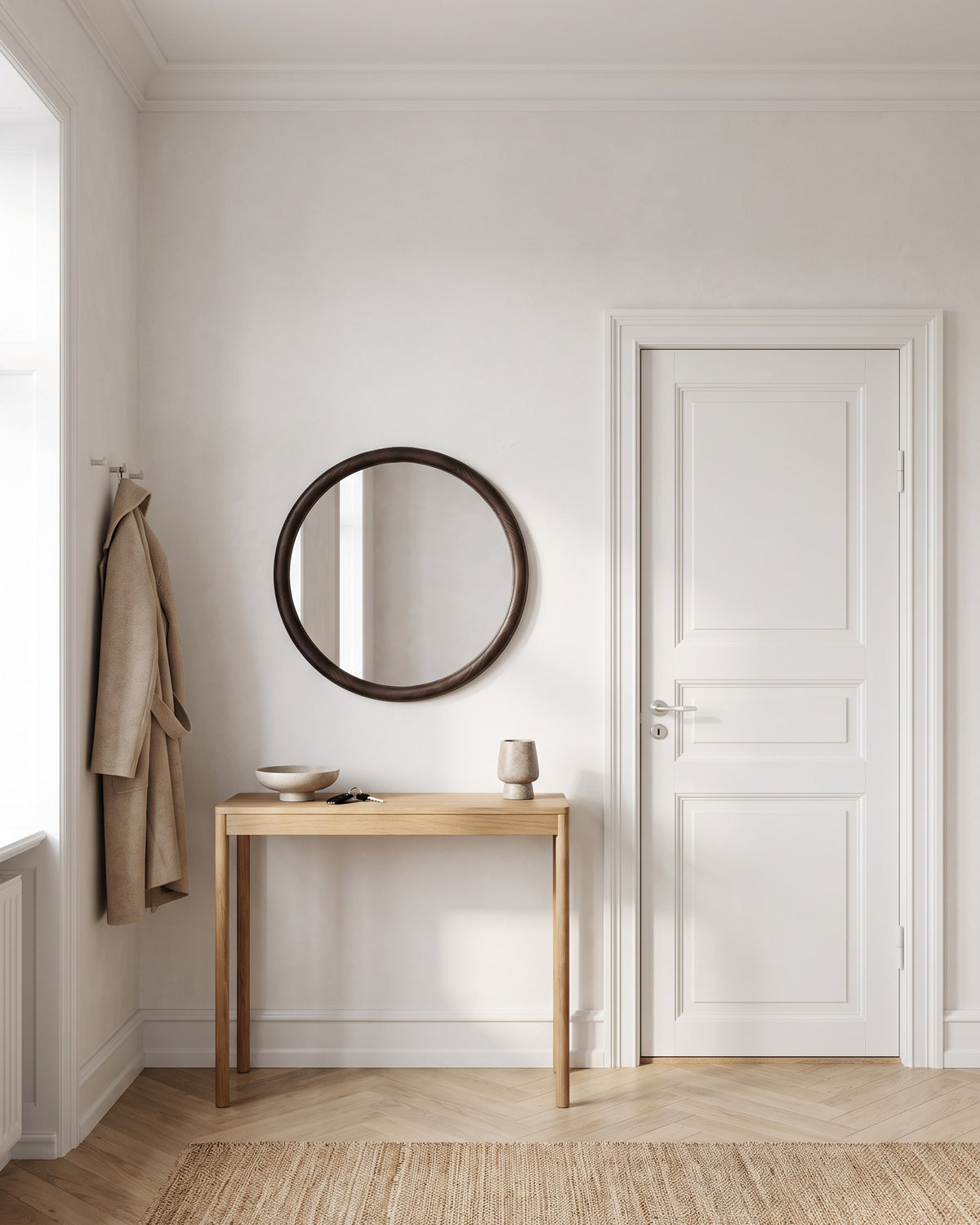 Enso round mirror Ø 70 cm above an oak console in an entrance hall with coat hooks and front door