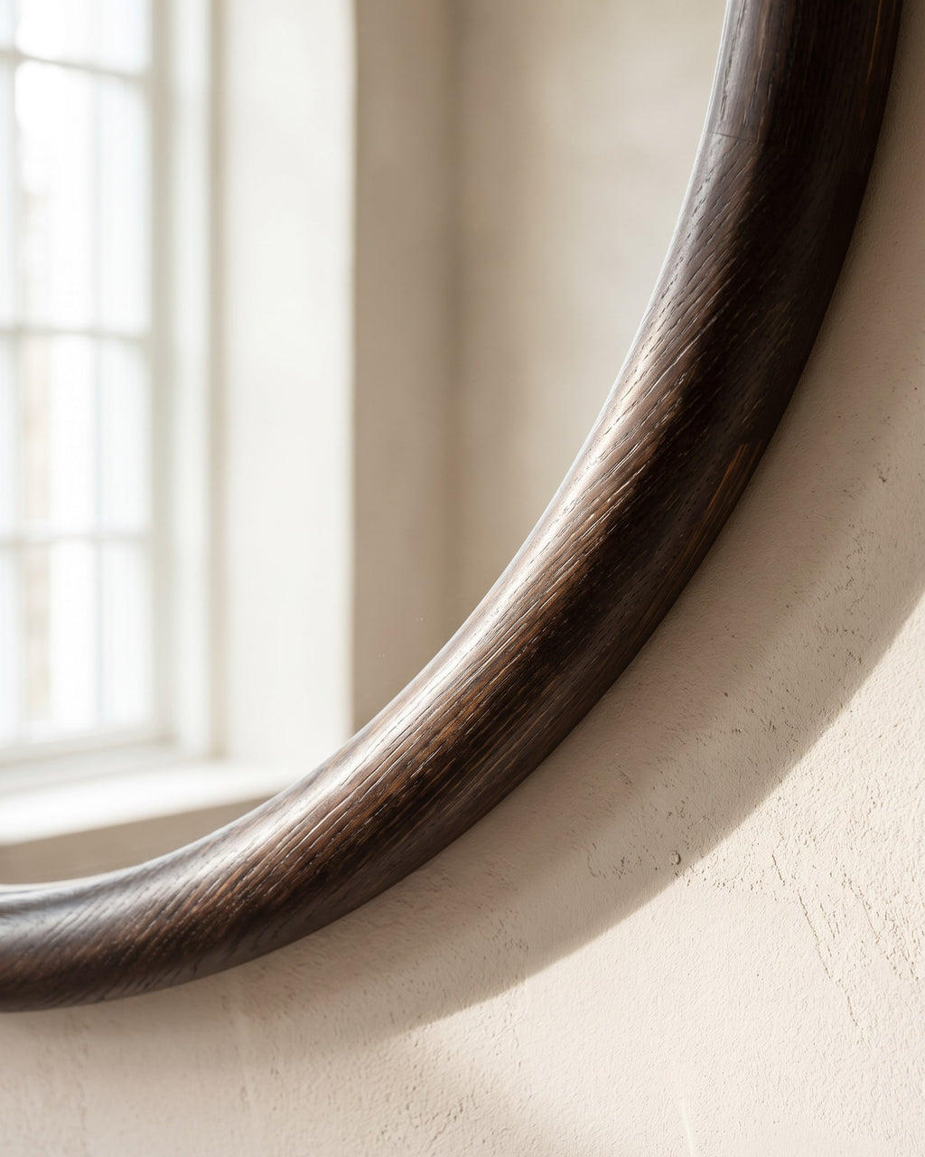 Close-up of the Enso mirror's rounded dark wood frame with visible grain