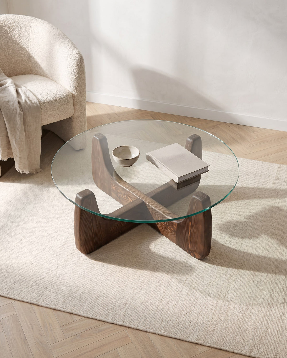 Selene round coffee table seen from above, cross-shaped walnut-finish base visible through the glass