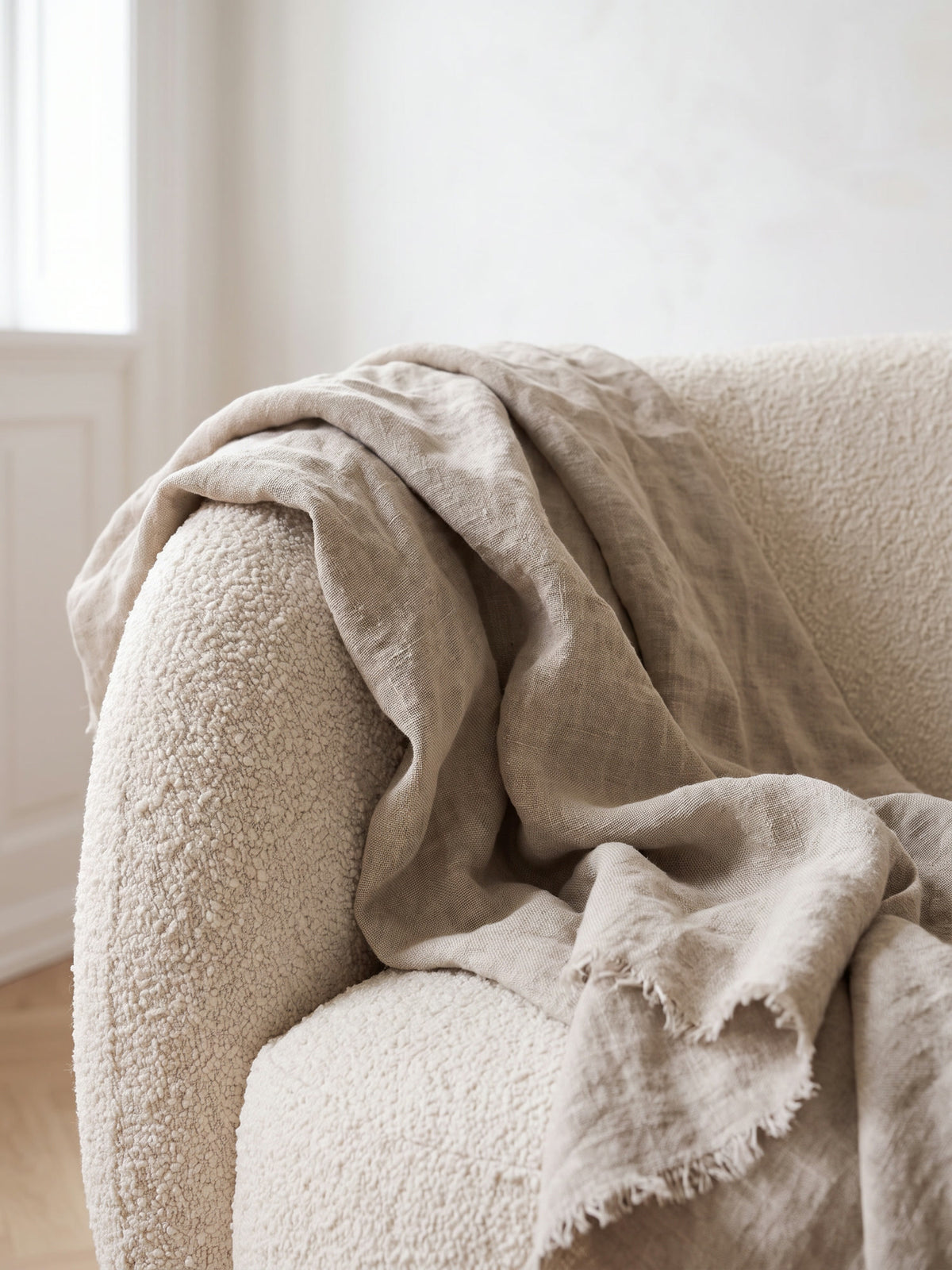Natural linen throw draped over the arm of a cream boucle sofa